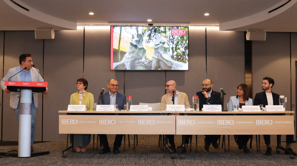 Man speaks at podium to panel, including directors from University of Notre Dame and Notre Dame Mexico, at Ibero.